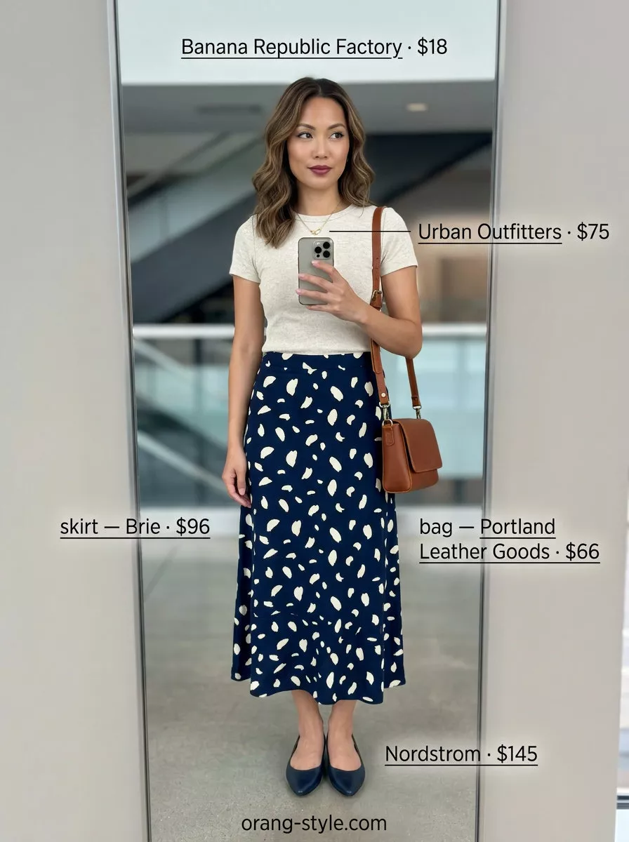 Lightweight summer office outfits for women 2026: Navy printed skirt, cream fitted top, and flats for an elegant look.