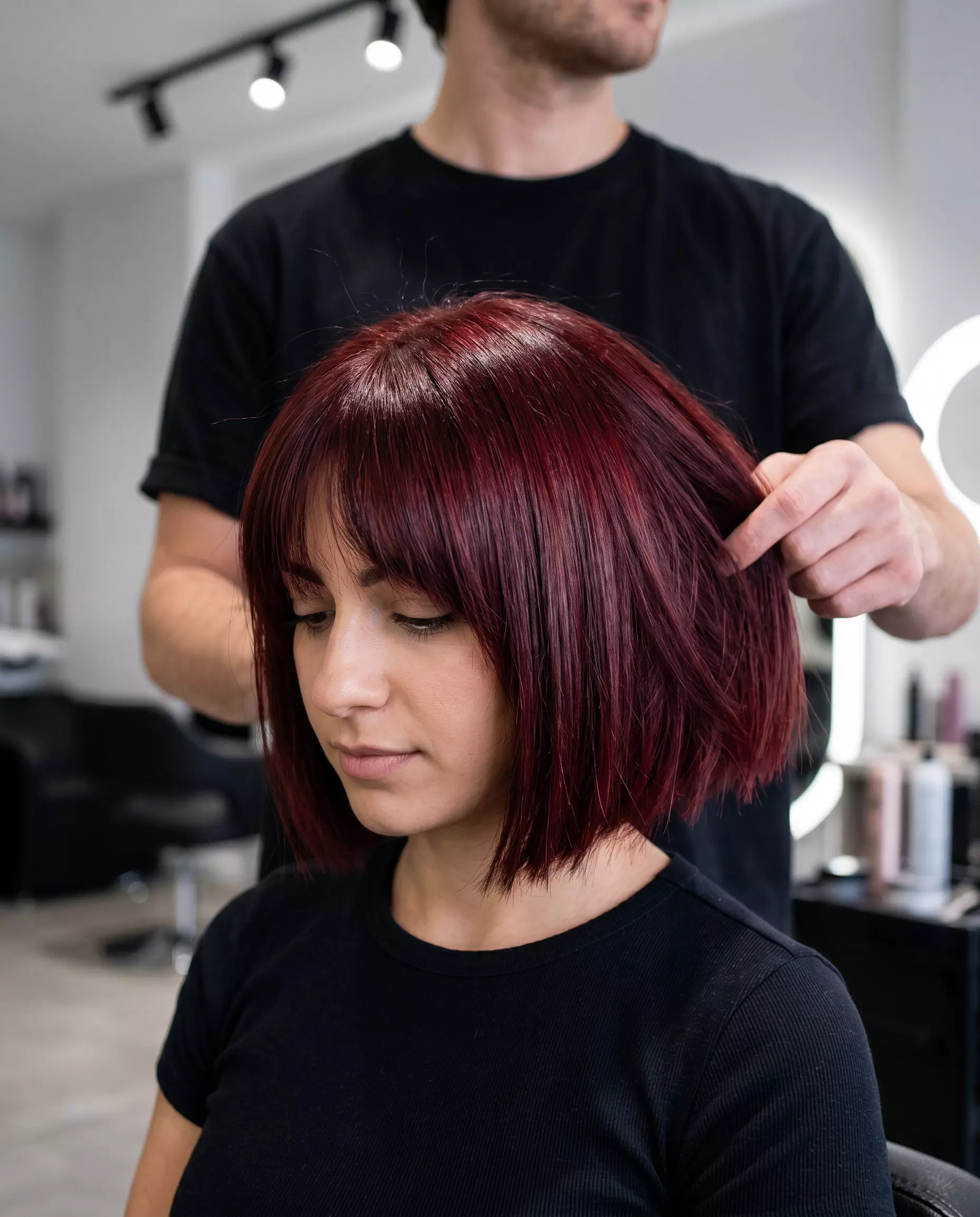 chin-length textured bob haircut with deep crimson ruby undertones and blunt fringe for a bold look