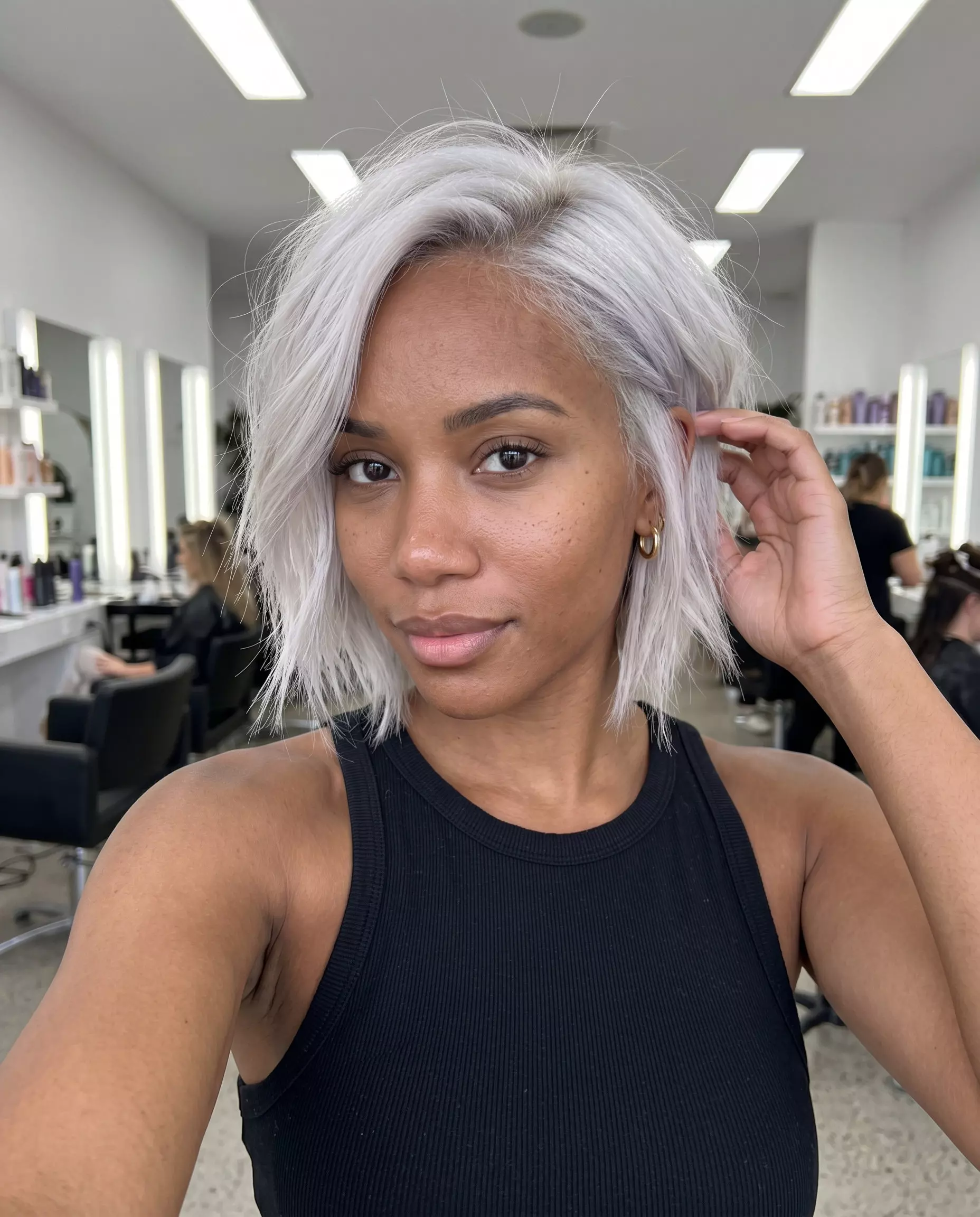 chin-length icy platinum bob haircut with razor-cut texture and side part for edgy look