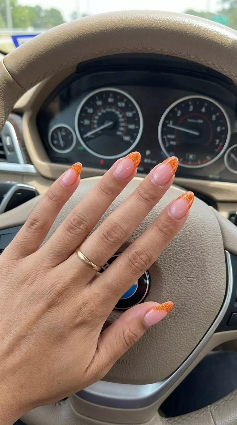 Glamorous orange glitter French tips on nude base. Neon summer nails 2026 for weddings.