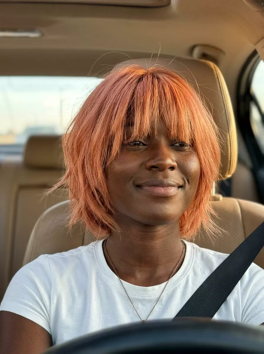 short shag haircut in soft peach copper with curtain bangs for playful look