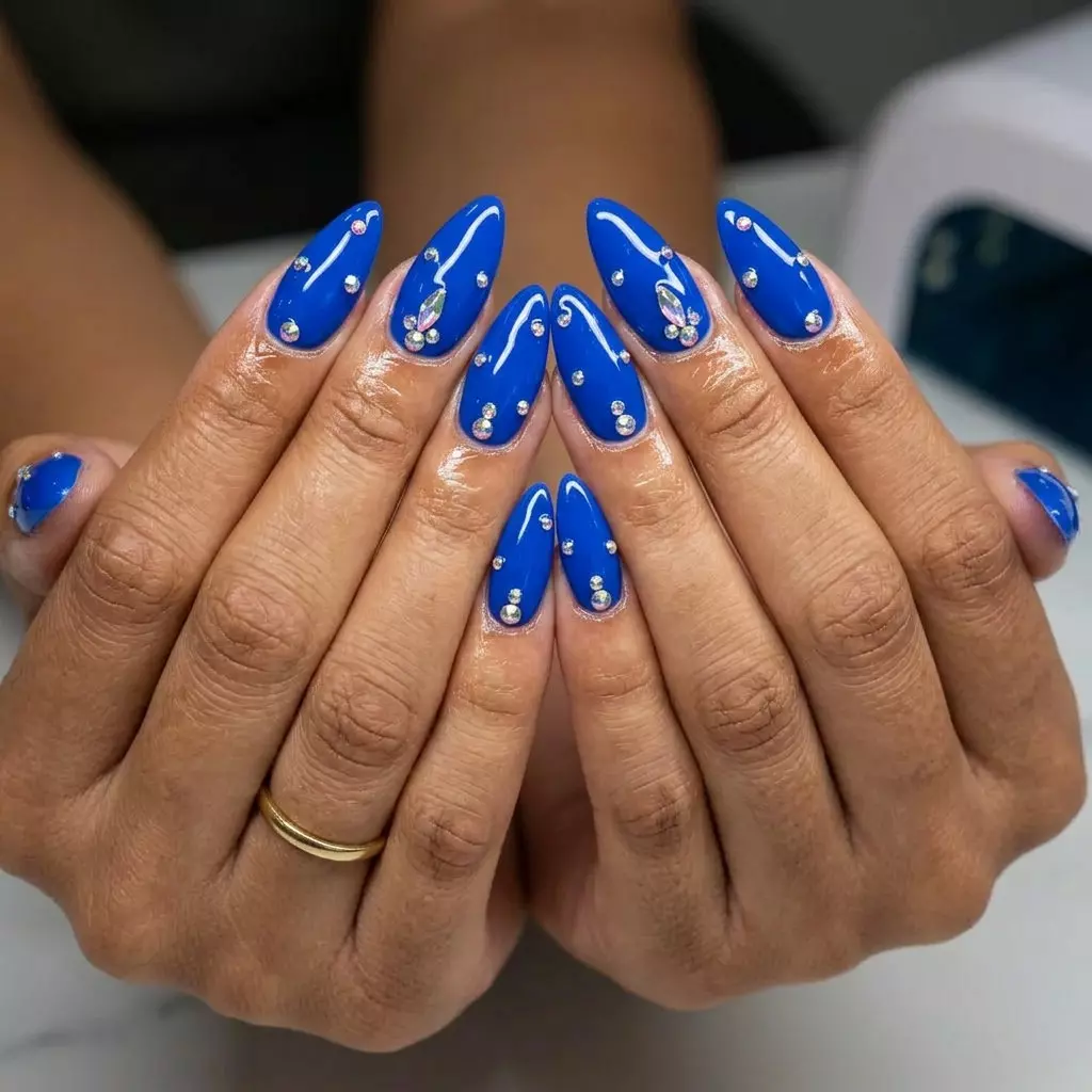 Glamorous cobalt blue stiletto nails with iridescent rhinestone sparkle for summer 2026.