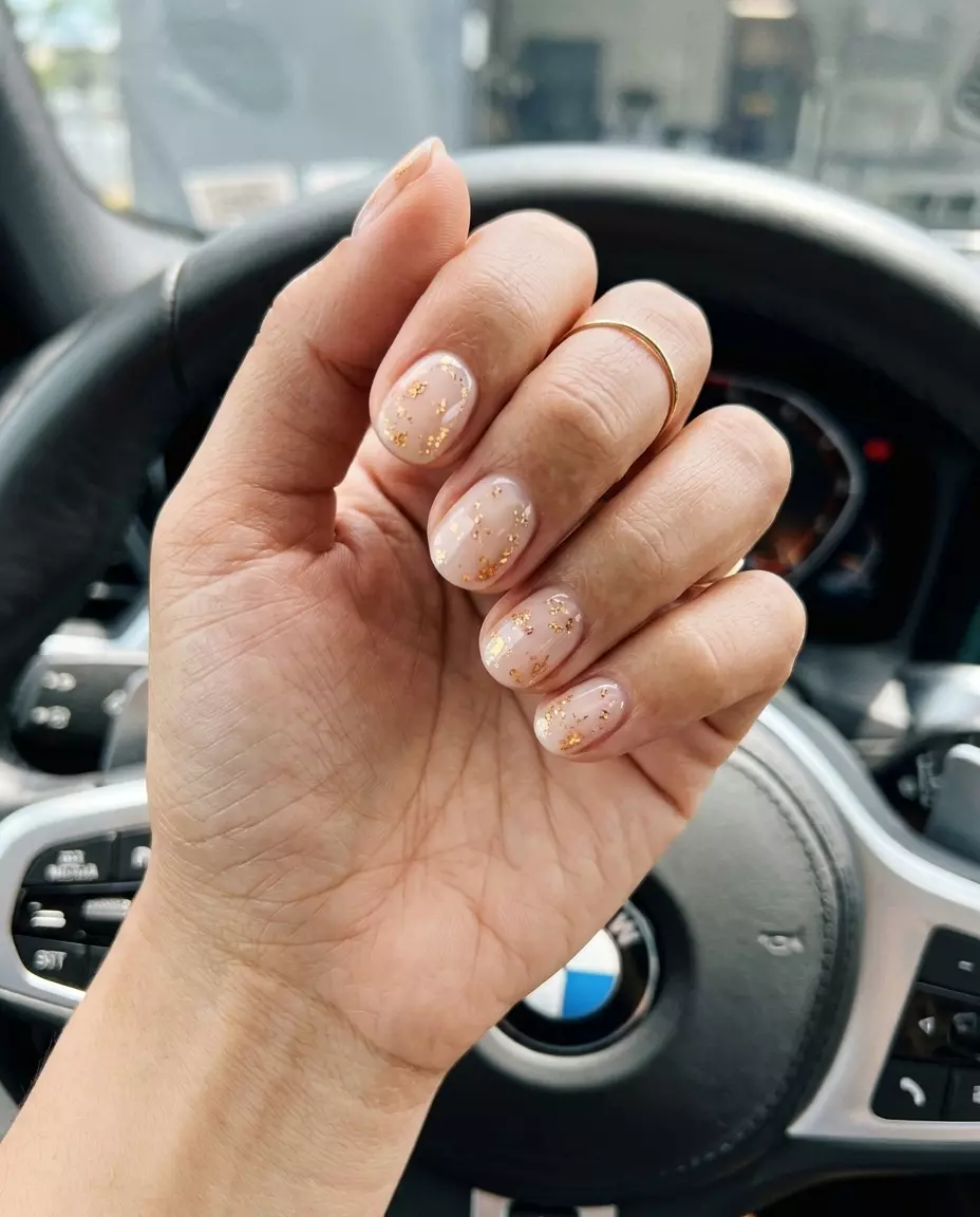 Chic milky nude with gold foil flakes for summer holiday nails 2026. Perfect for work or casual outings.