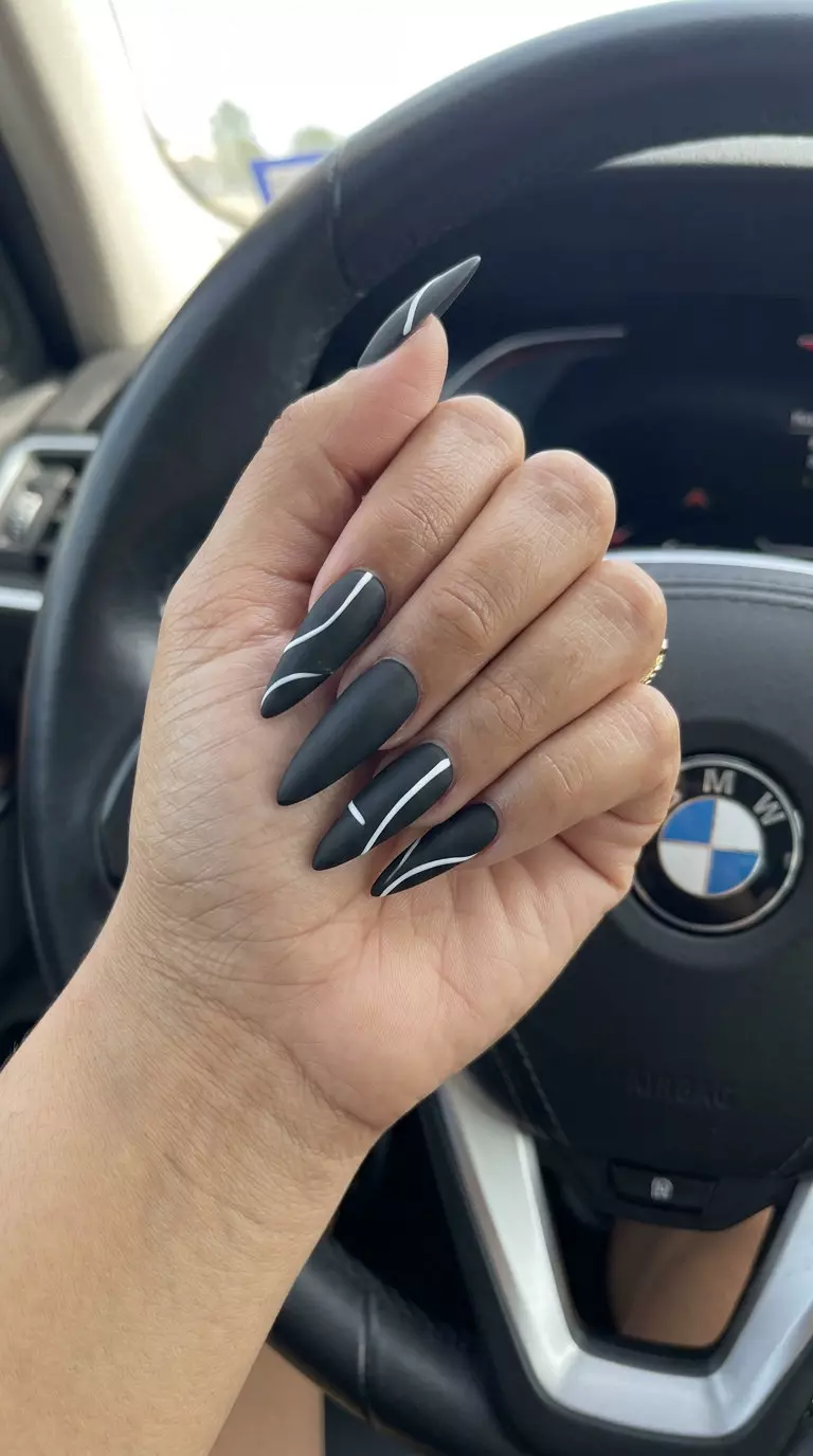 Summer Matte Nails 2026: Bold Black Stiletto Lines Summer matte nails 2026: Deep matte black with sharp white abstract lines on stiletto nails for night out.